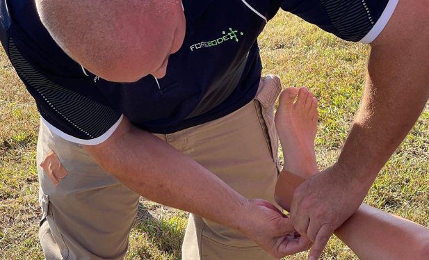 Professional Sports Paramedic assisting Athlete taping their feet at Forbode