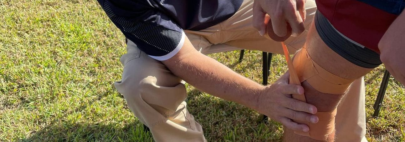 Professional Sports Paramedic assisting Athlete taping their knees at Forbode